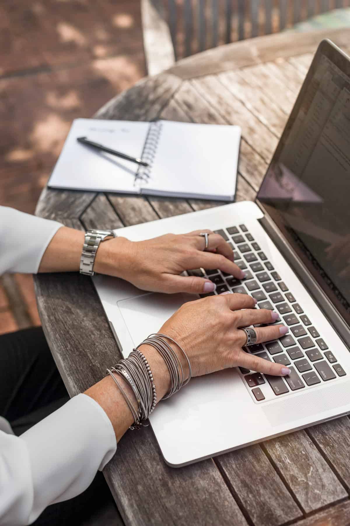 blogger typing on laptop with silver jewelry on